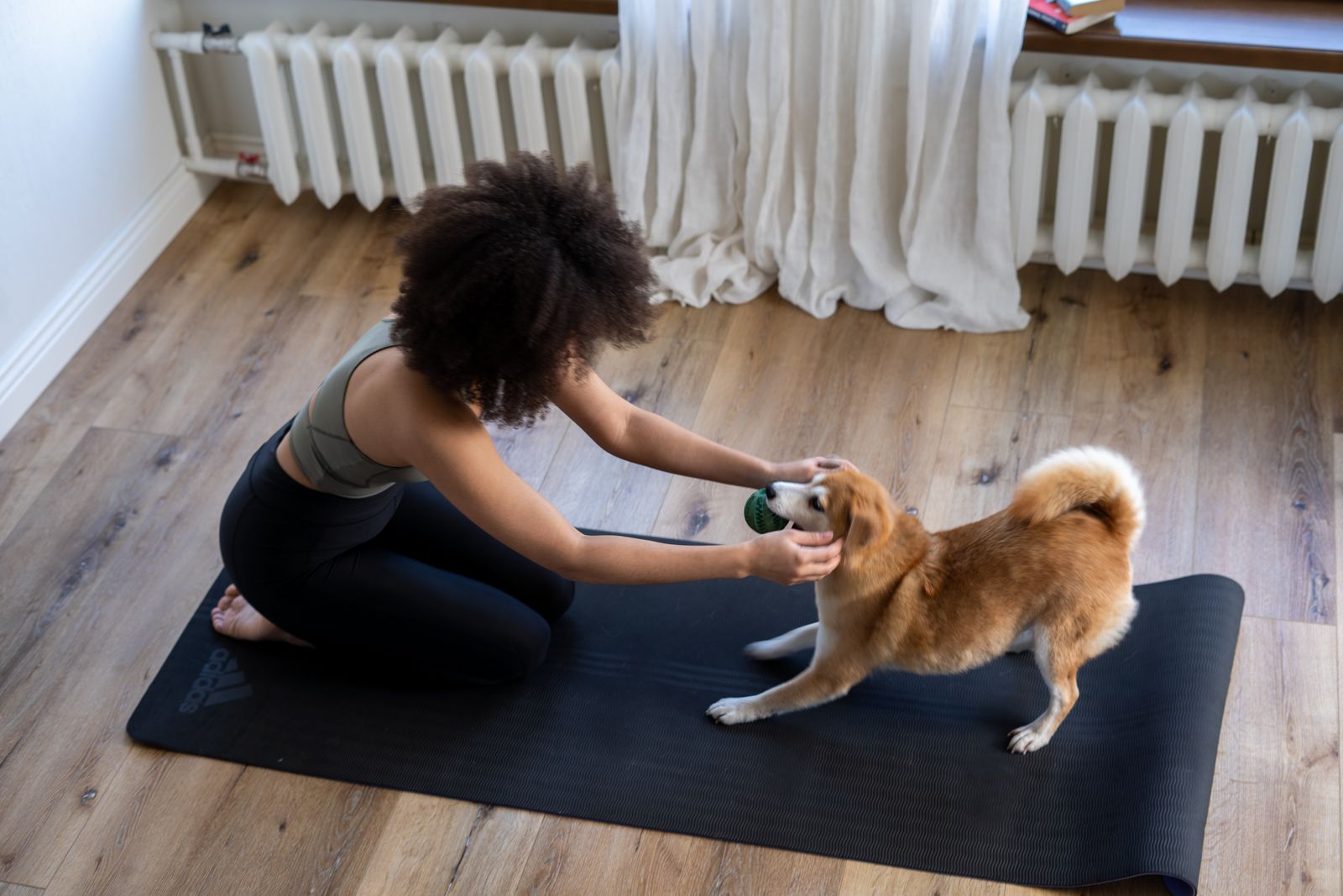 A woman taking a relaxed break on a yoga mat with her dog